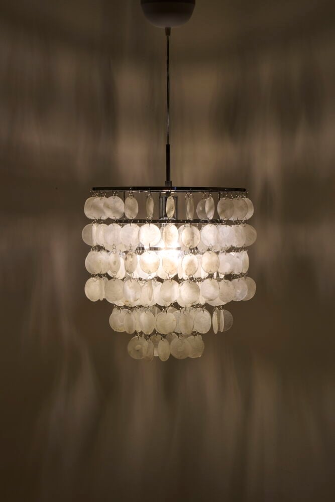 Modern taklampa med vita glashängen och metallram.