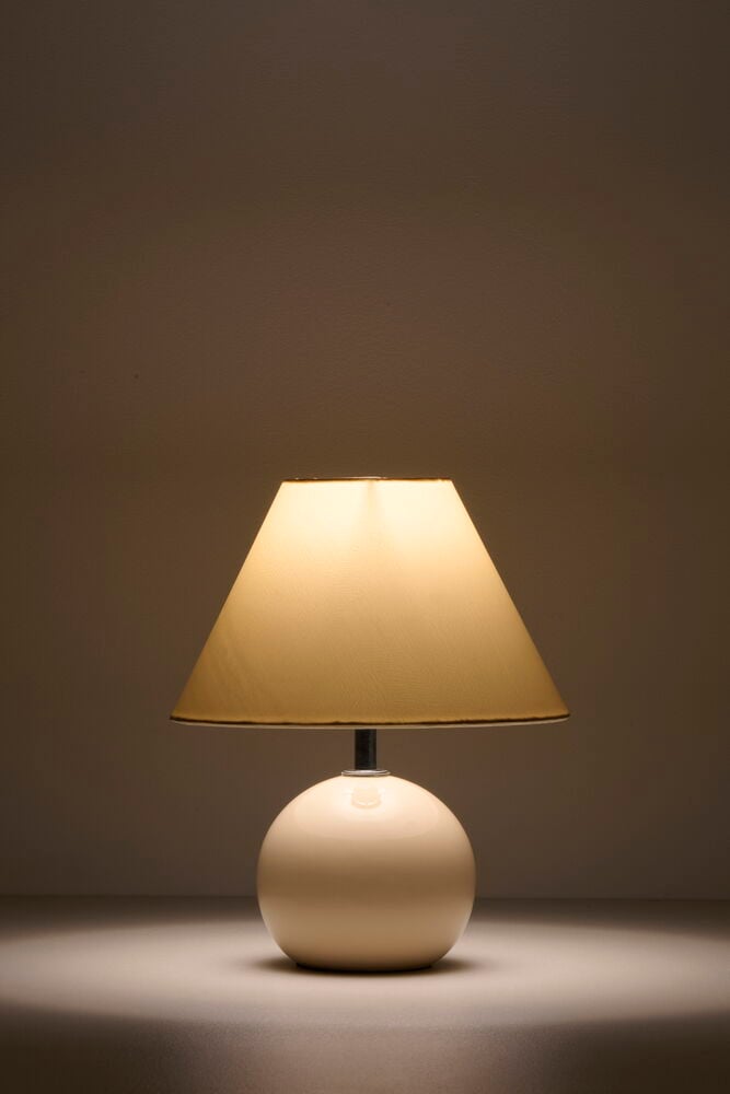 Beige bordslampa med rund fot och konisk skärm.