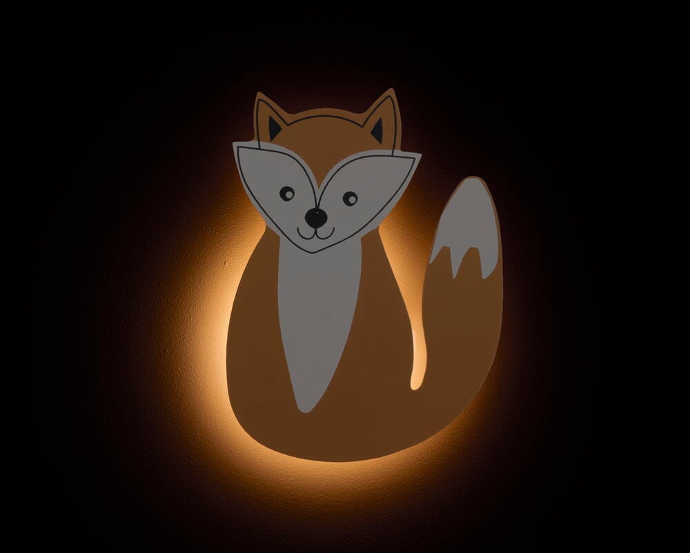 Rävformad dekorationslampa som lyser på väggen.