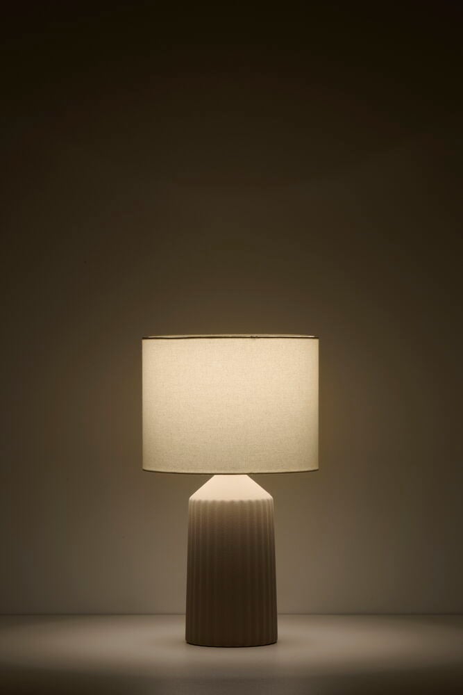 Vit bordslampa med räfflad fot och tygskärm.