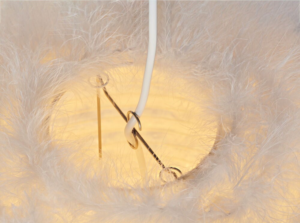 Närbild av fluffig vit taklampa med ljus inuti.