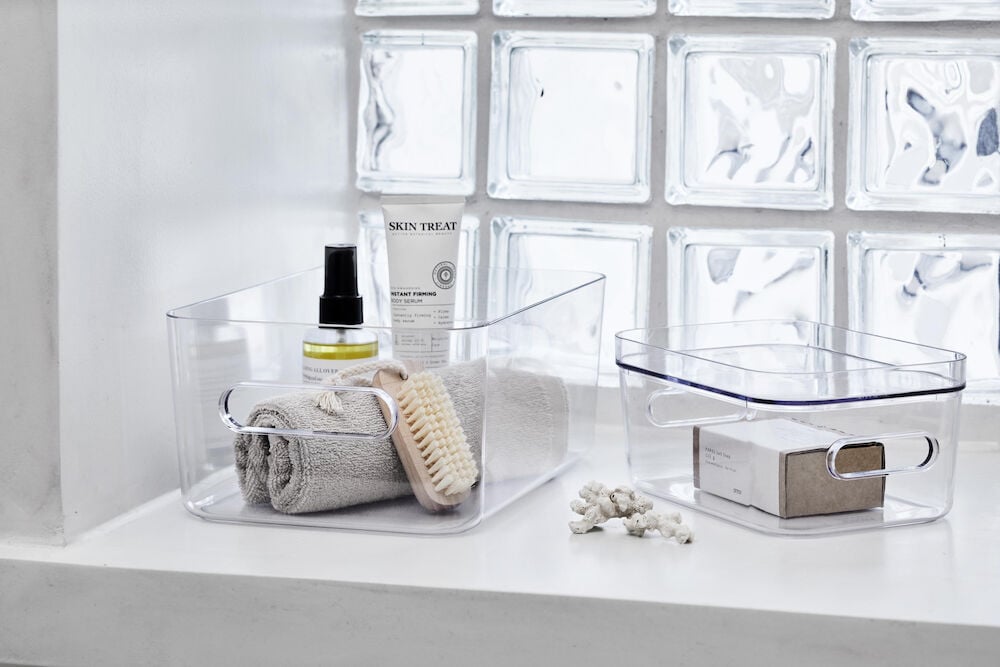 Två transparenta förvaringslådor med hygienartiklar på hylla.