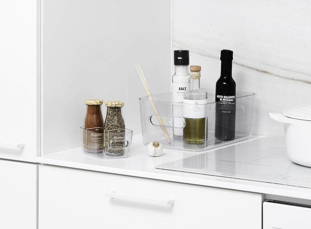 Transparent förvaringslåda med matvaror på vit bänk.