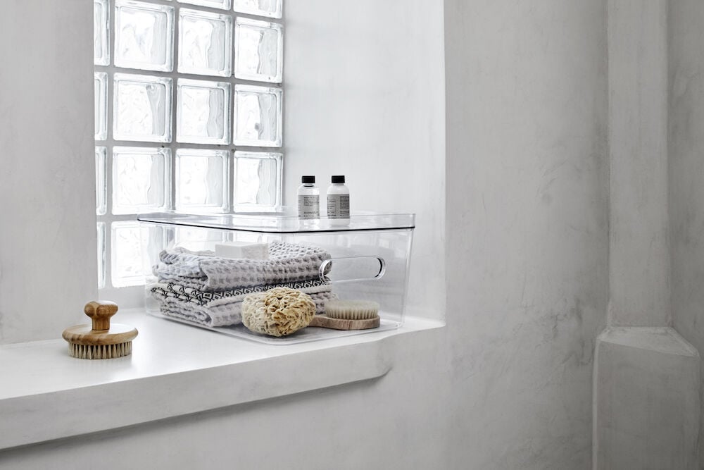 Transparent förvaringslåda med handtag och handdukar.