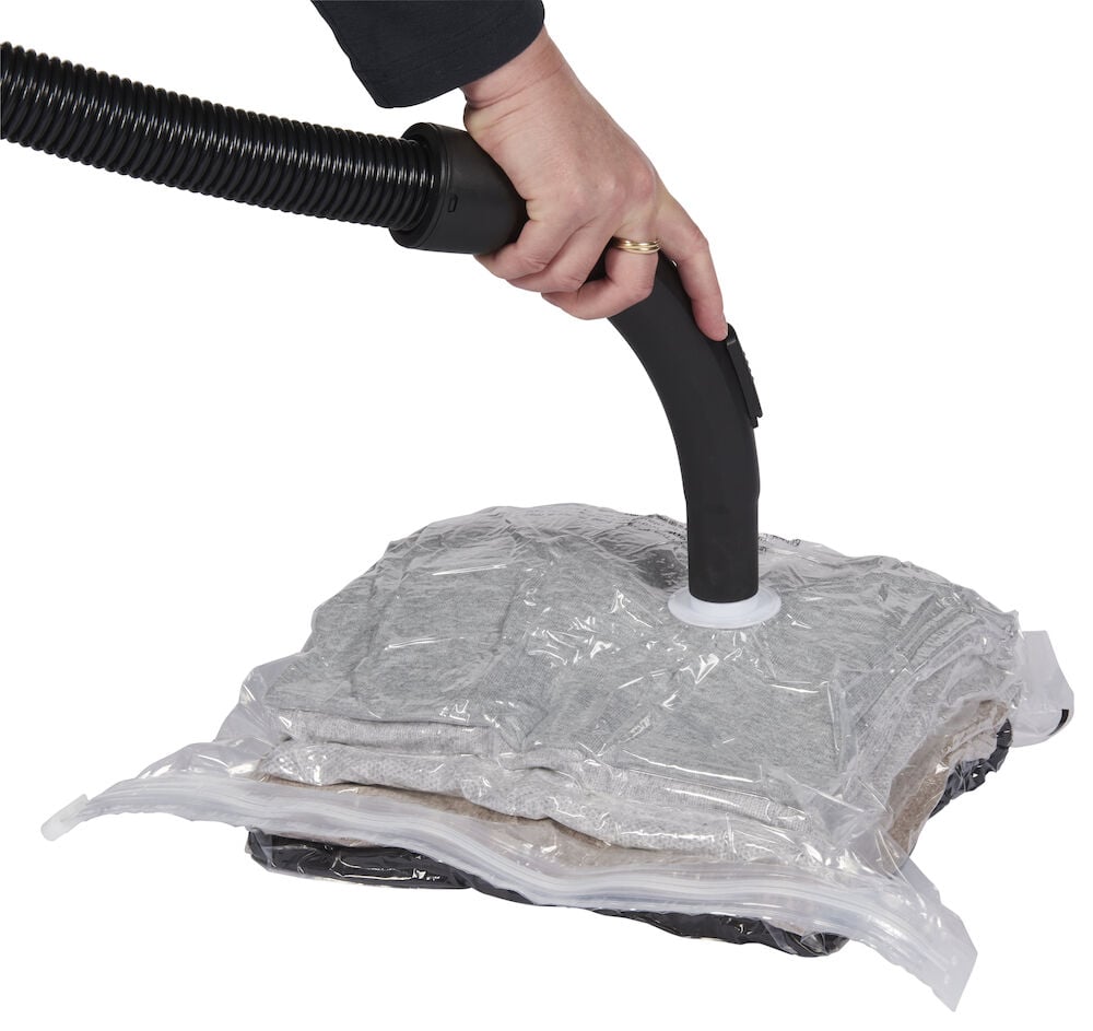 Vakuumpåse med kläder sugs ur med dammsugare.