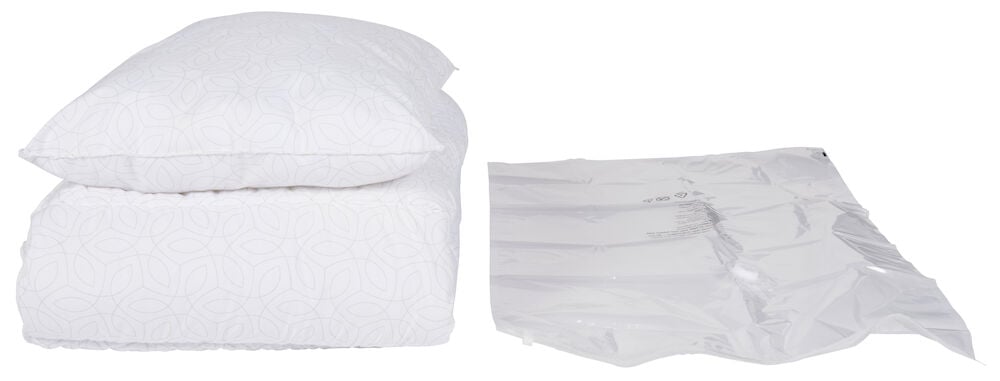 Kudde och täcke bredvid tom vakuumpåse.