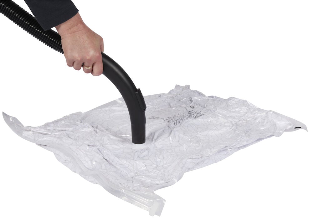 Hand dammsuger genomskinlig vakuumpåse fylld med textilier.
