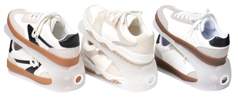 Drei Paar Turnschuhe auf transparenten Schuhhaltern aus Kunststoff.