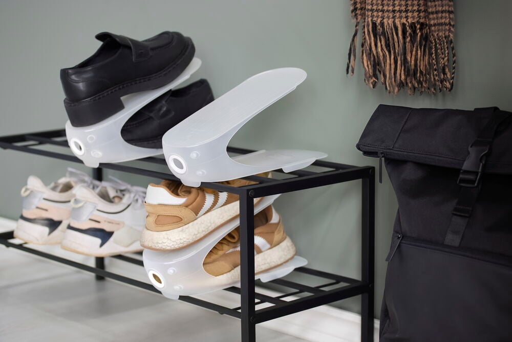 Transparenter weißer Schuhhalter 1 er-Pack Polypropylen hält schwarze Slipper, Sneaker, neben schwarzem Rucksack und Schal.