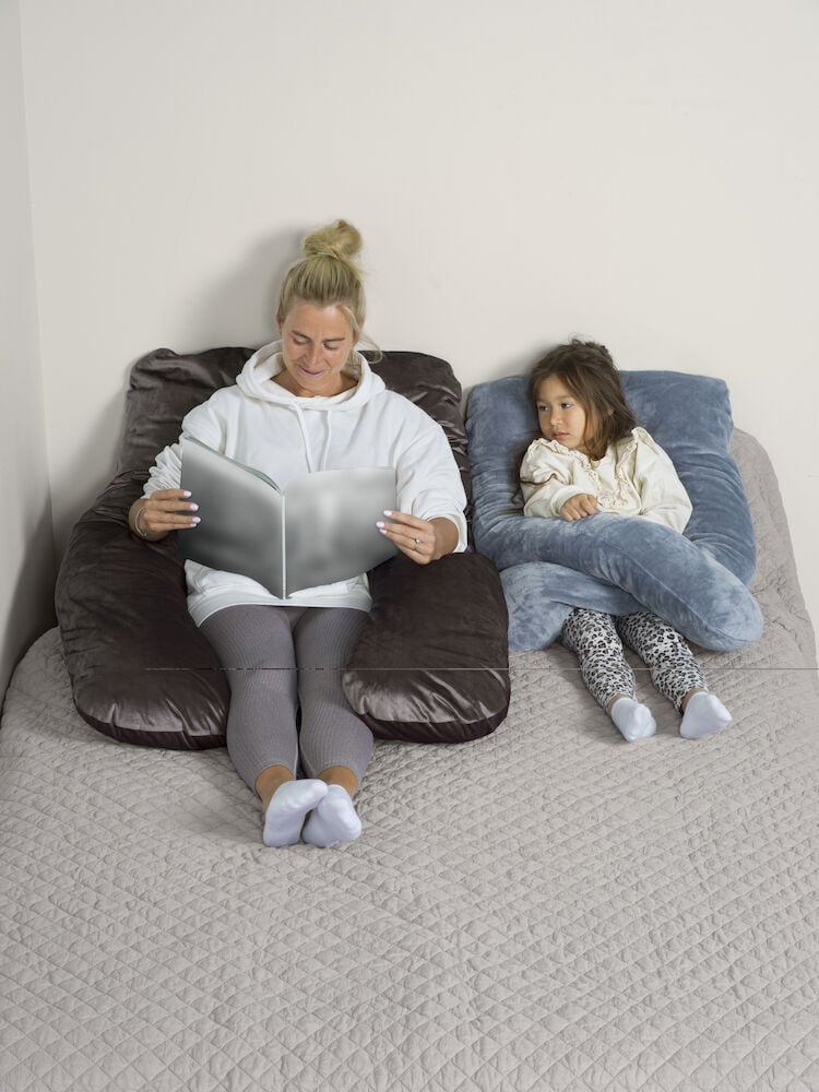 Nainen ja lapsi sängyllä vartalotyynyjen kanssa.