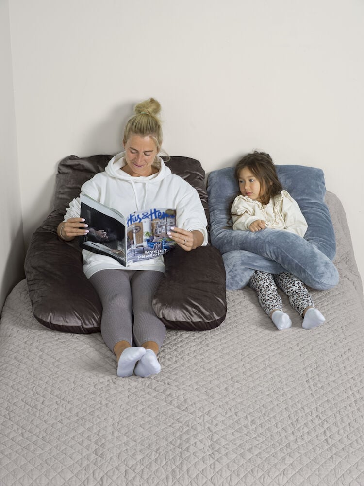 Kaksi henkilöä lepää u-muotoisilla vartalotyynyillä.