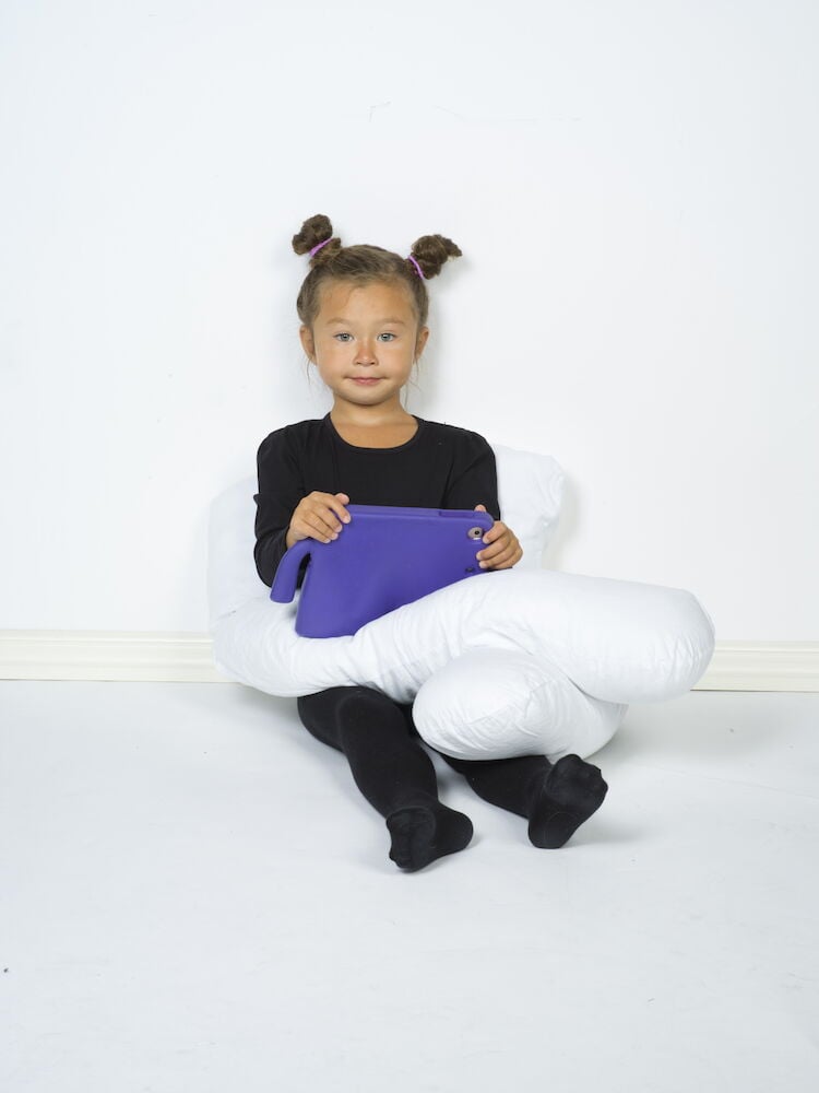 Lapset istuvat U-muotoisen vartalotyynyn kanssa.