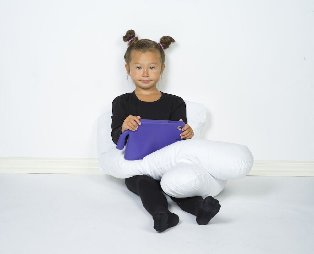 Tyttö istuu U-muotoisen vartalotyynyn kanssa.