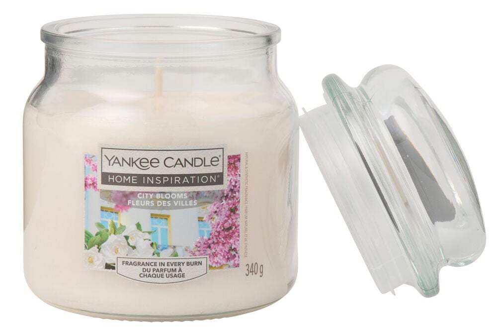 Hvitt City Blooms duftlys i klar glasskrukke med matchende glasslokk plassert ved siden av.