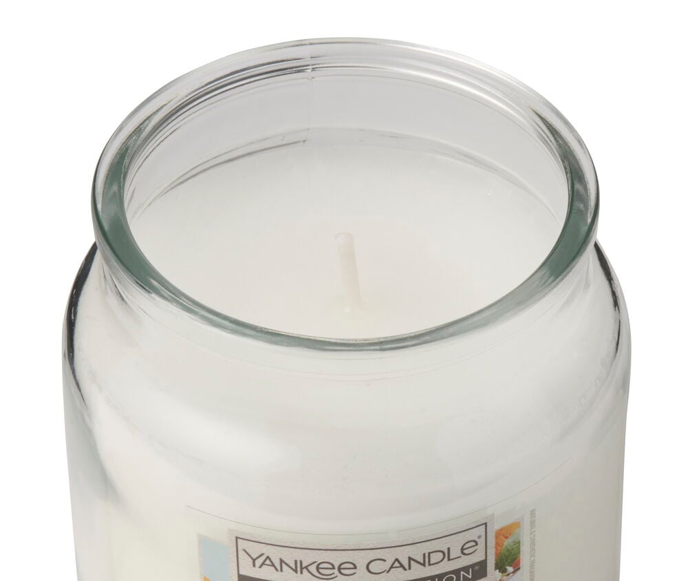 Et nærbilde viser et hvitt Duftlys Yankee Candle Sweet Orange Blossom i en klar glasskrukke med en veke.