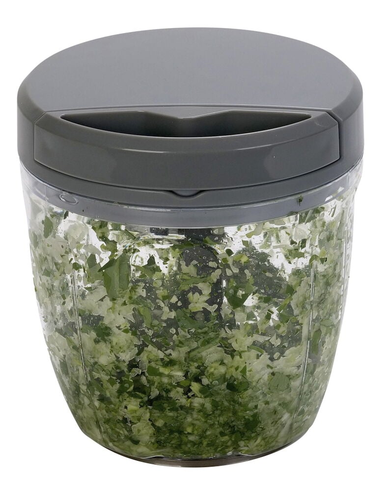 Manuelle Minihacker mit grauem Deckel und gehackten Kräutern.