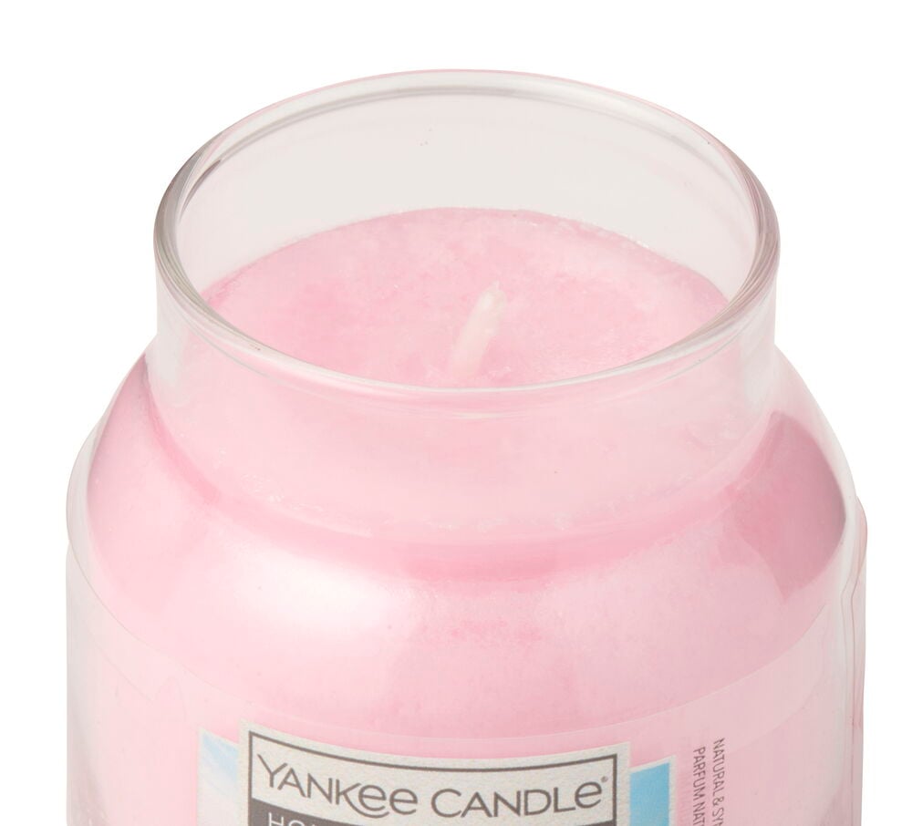 Nærbilde av et rosa duftlys i en klar glasskrukke med en hvit veke.