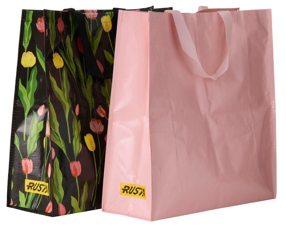 Rosa Handlepose Large Spring og en svart blomstret handlepose med gule etiketter.