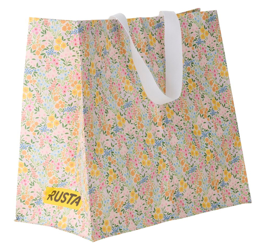 Ostoskassi Medium Kevät, jossa vaaleanpunainen pohja, monivärinen kukkakuvio, valkoiset kahvat ja RUSTA-logo.