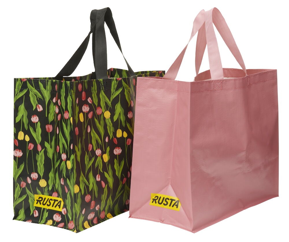 Ostoskassi Medium Kevät tummalla tulppaanikuviolla ja mustilla kahvoilla, sekä yksivärinen vaaleanpunainen ostoskassi.