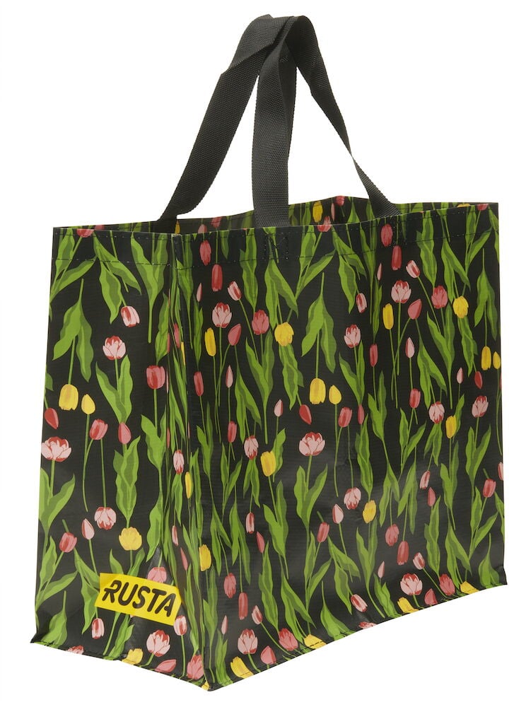 Ostoskassi Medium Kevät, musta vihreillä lehdillä ja värikkäällä tulppaanikuviolla, mustat kahvat ja keltainen Rusta-logo.