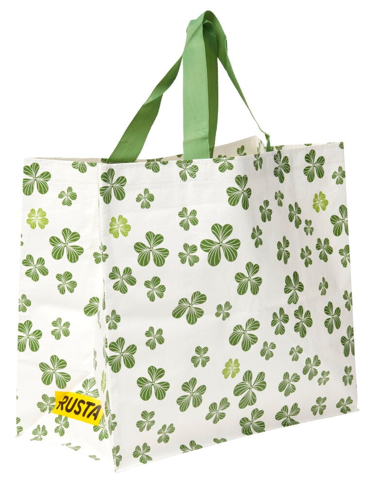 Ostoskassi Medium Kevät, valkoinen vihreillä apilakuvioilla, vihreät kahvat ja keltainen lappu.