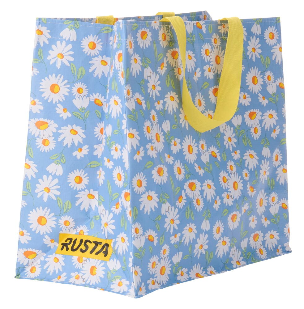 Ostoskassi Medium Kesä sinisenä valkoisella päivänkakkarakuviolla ja keltaisilla kahvoilla, RUSTA-logolla.