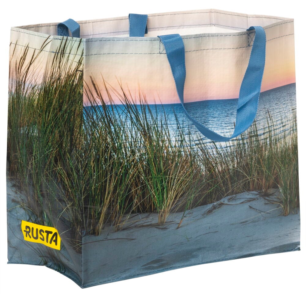 Einkaufstasche mit Strandmotiv und blauen Griffen.