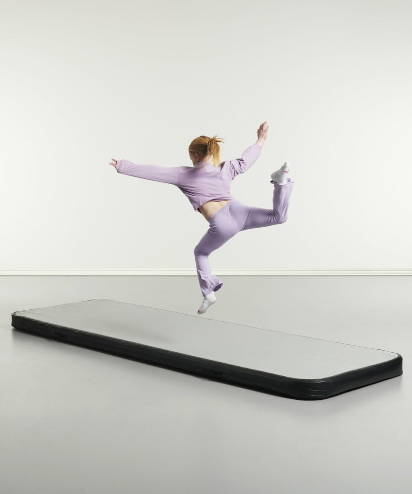 Jente hopper på svart og grå airtrackmatte.