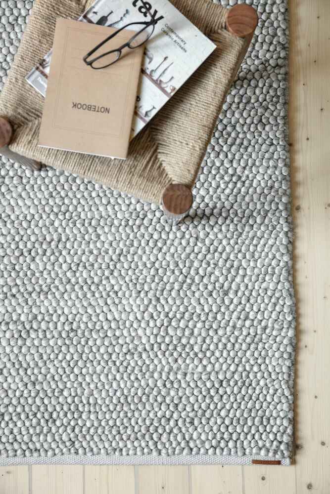 Käsinkudottu harmaa villamatto, jossa on rakennettu pinta.