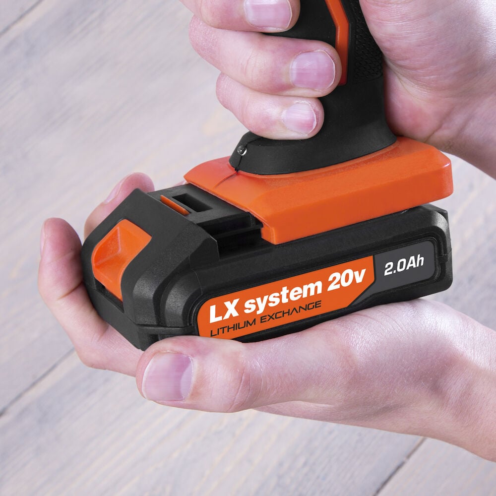 Svart och orange batteri i händer på trägolv.