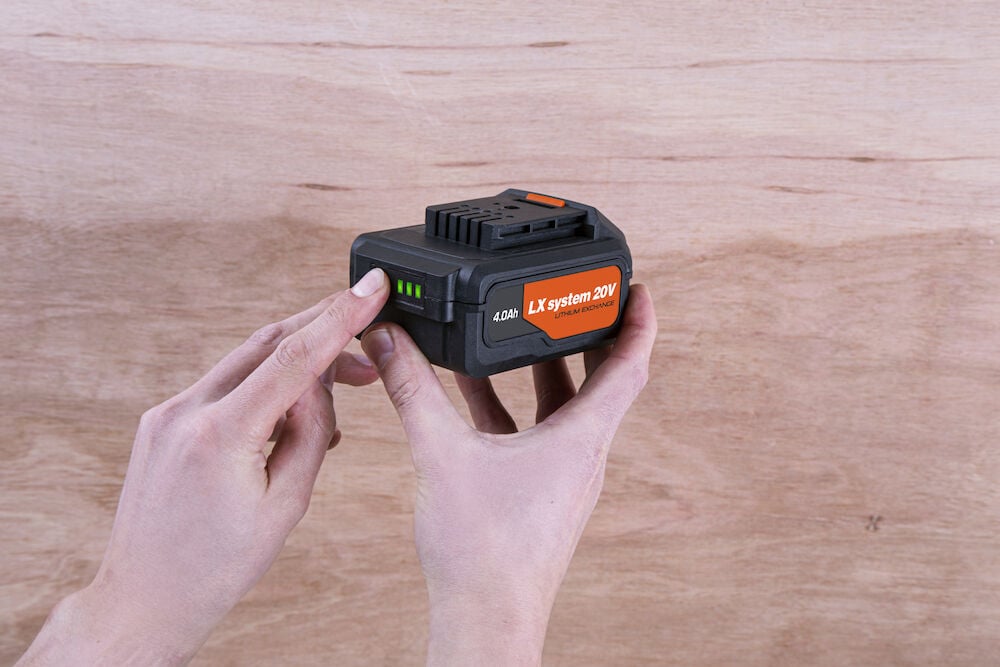 Person håller i ett svart 20V uppladdningsbart batteri.