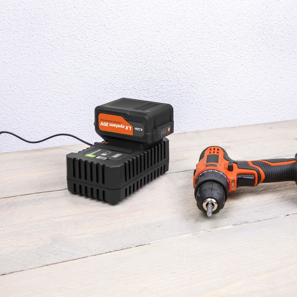 Batteridriven skruvdragare och batteriladdare på träbord.