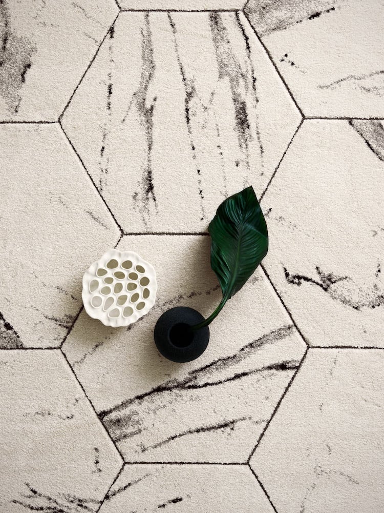 Valkoinen matto kuusikulmiomallilla ja kaksi koriste-esinettä.