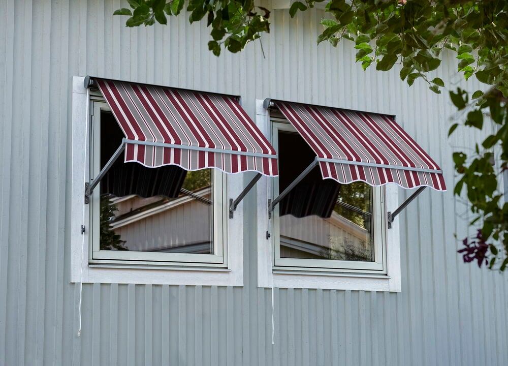 Zwei Fenstermarkisen mit burgunderroten, grauen und weißen Streifen sind an einem hellgrauen Gebäude montiert.