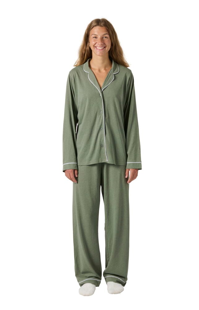 Kvinna i grön Pyjamas Laura med vit passpoal och vita fluffiga tofflor, framifrån.