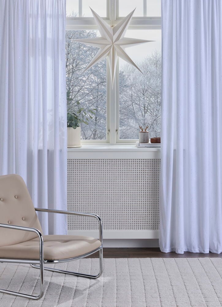 Vorhang Angelstad 135x250 cm in weißem Polyestersamt mit Funkeln hängt an einem Fenster.