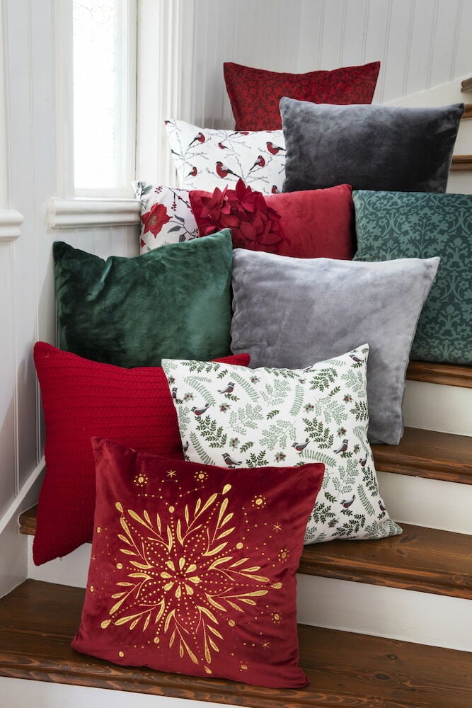 Flera kuddfodral i olika färger på en trappa.