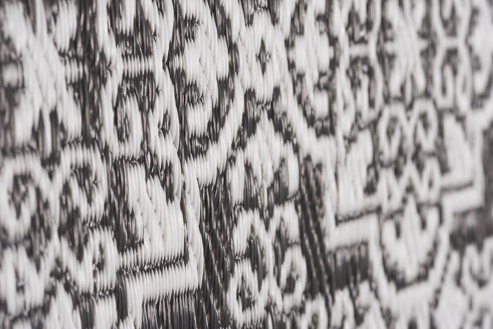 Närbild av bastmatta med svartvitt dekorativt mönster.