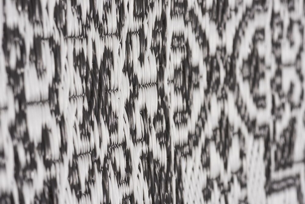 Närbild av antracitfärgad polypropenmatta med dekorativt mönster.