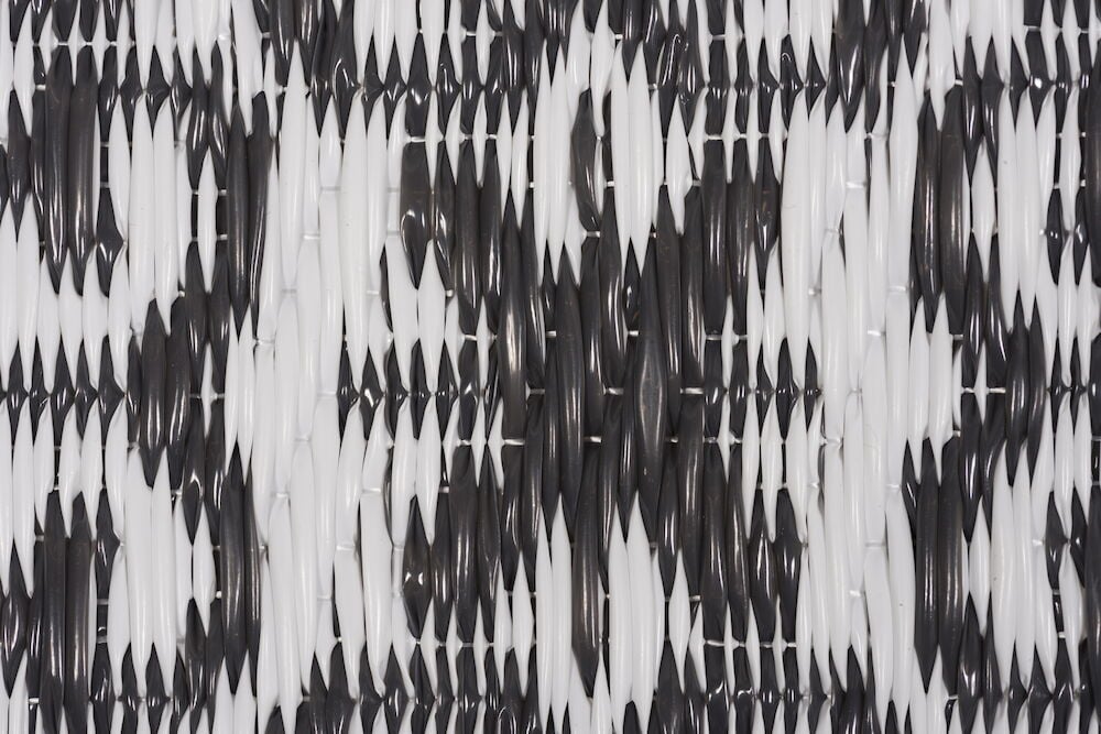 Närbild av bastmatta i antracit och vitt mönster.