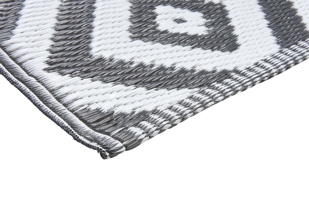 Hjørnet av et gråhvitt polypropylen-teppe med mønster.