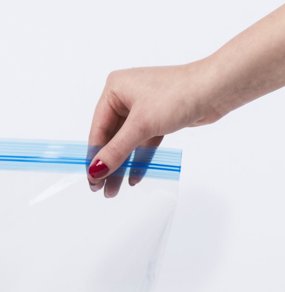 Käsi pitää läpinäkyvää pakastuspussia, jossa on sininen vetoketju.