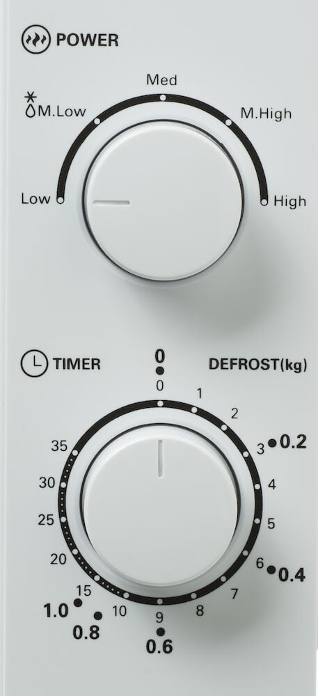 Nahaufnahme des weißen Bedienfelds der Mikrowelle mit zwei Drehknöpfen.