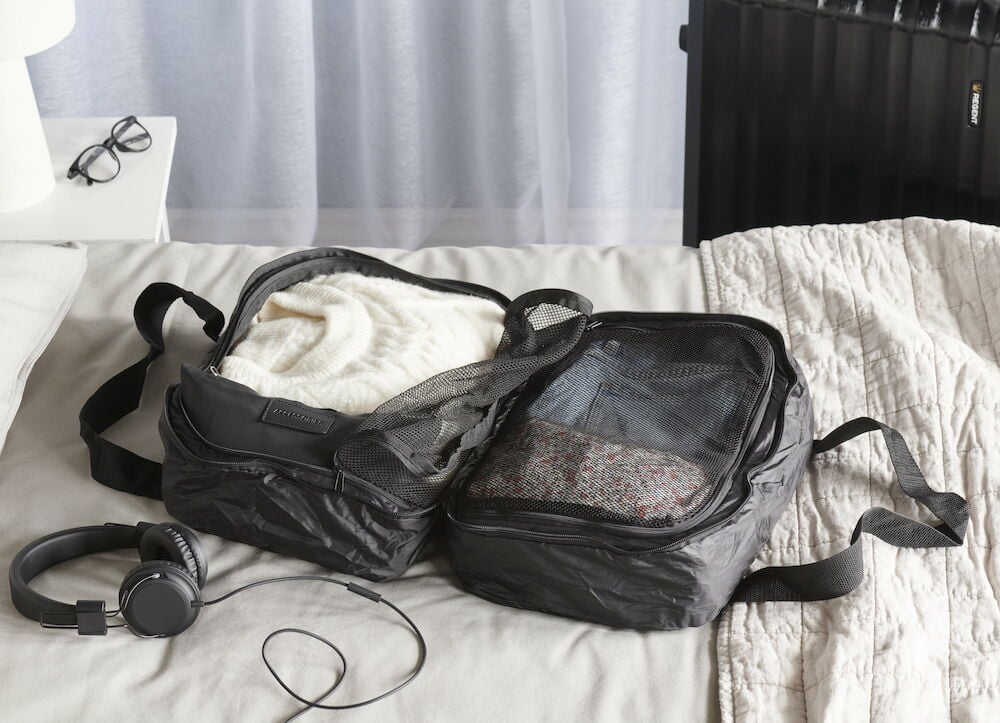 Svart duffelbag öppen med kläder och meshfickor.