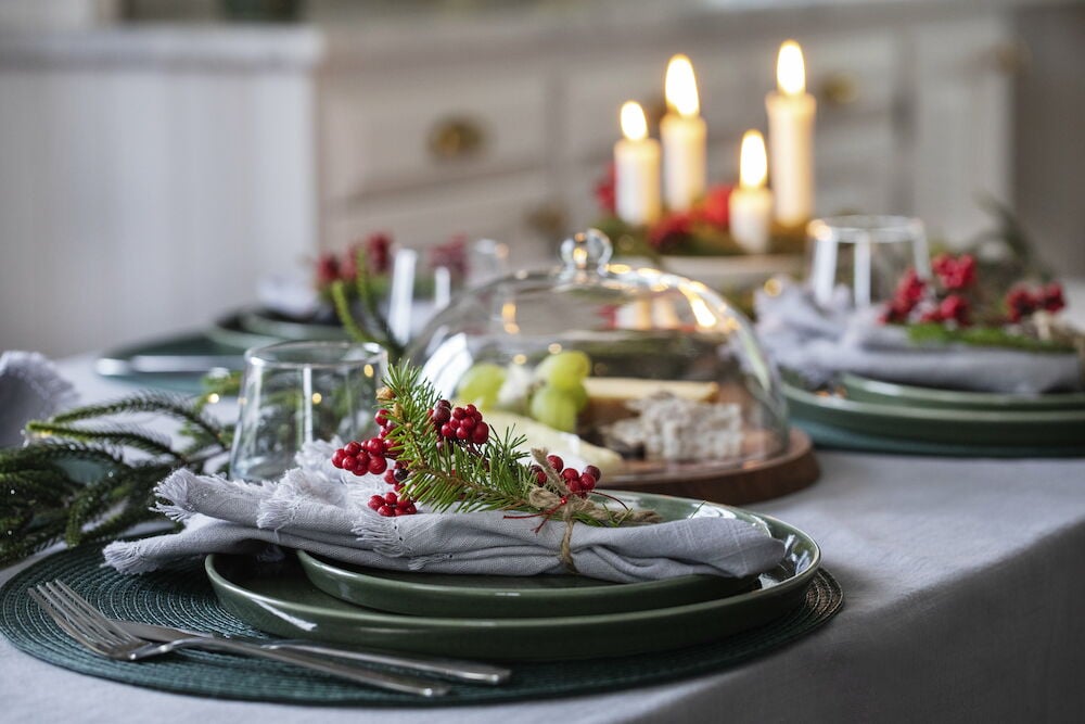 Hellgraue Tischdecke mit Fransen auf gedecktem Tisch.