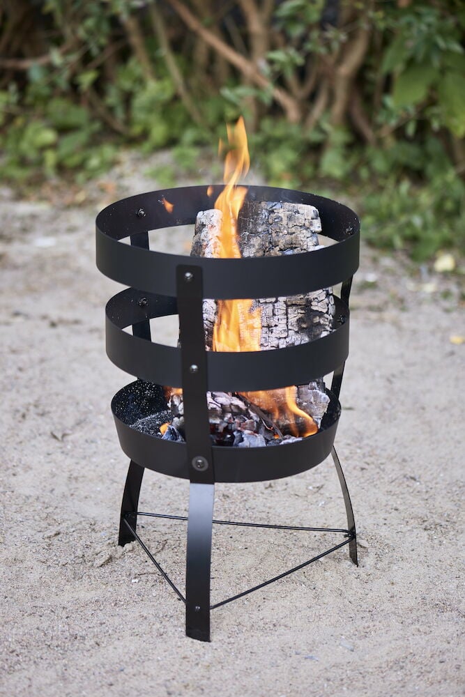 Svart eldkorg utomhus med brinnande ved och eld.