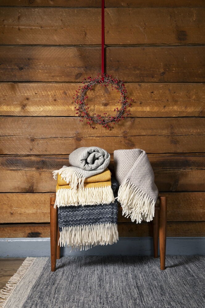 Grauer handgewebter Wollteppich mit Fransen auf dem Boden.