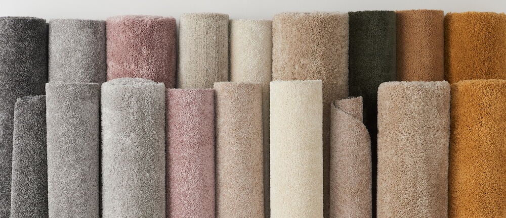 Flera upprullade mattor i olika färger och nyanser.