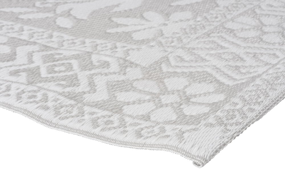 Hörnet av silverfärgad bastmatta med mönster.